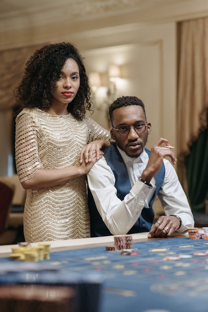 about-01 Sophisticated couple sitting with poker chips at a luxurious casino table indoors.