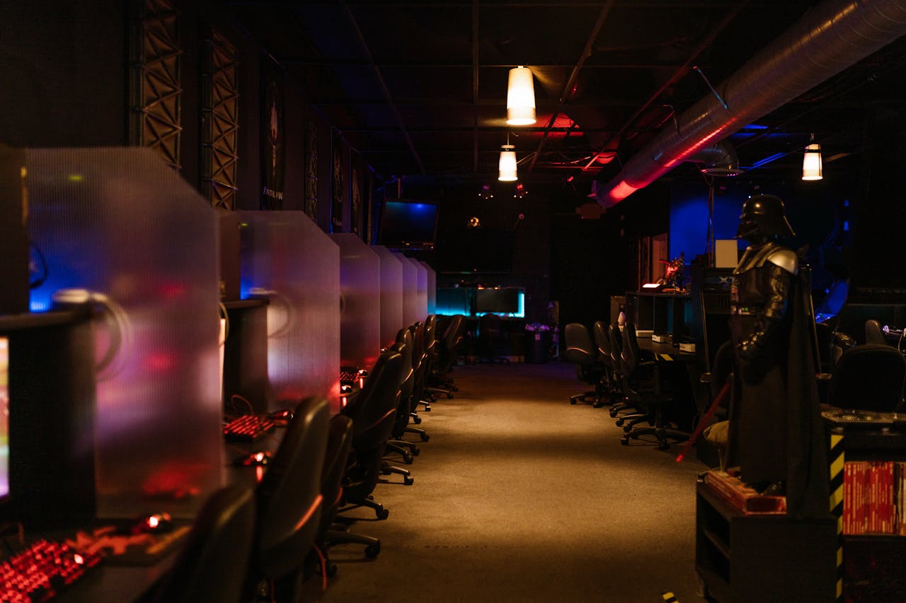 services-03 A dimly lit gaming arcade with neon lights and computers, creating a futuristic atmosphere.